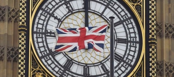 A British Union flag flutters in front of one of the clock faces of the 'Big Ben' clocktower of The Houses of Parliament in central London